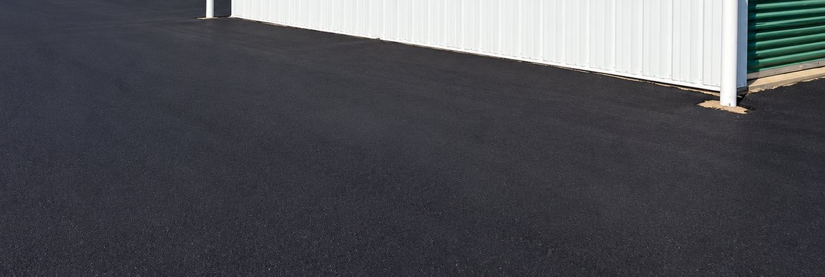 New black asphalt beside a storage building